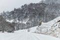 Empty mountain asphalt road in winter covered with snow on a cloudy day. The concept of driving a car in winter ice and Royalty Free Stock Photo