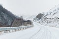 Empty mountain asphalt road in winter covered with snow on a cloudy day. The concept of driving a car in winter ice and Royalty Free Stock Photo