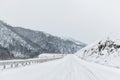 Empty mountain asphalt road in winter covered with snow on a cloudy day. The concept of driving a car in winter ice and Royalty Free Stock Photo