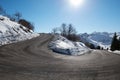 Empty mountain road curve on Alps with snow on sides, blue sky Royalty Free Stock Photo