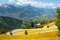 Empty mountain road runs past the beautiful yellow meadows in the French Alps. Royalty Free Stock Photo