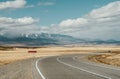 Empty mountain road with a single car and traffic sign. Blue sky, yellow grass Royalty Free Stock Photo