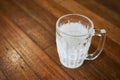 An empty mug for beer covered with hoarfrost stands on a wooden table of a pub Royalty Free Stock Photo