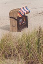 Empty multicolord roofed chair on sandy beach in Travemunde, North Germany. Dune with dry grass in foreground Royalty Free Stock Photo