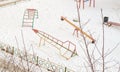 Empty multicolored metal children's swings and slides on the playground on a frosty winter day in the city park Royalty Free Stock Photo