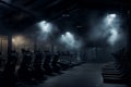 Empty night gym displaying various exercise machines and equipment surrounded by dim backlighting and smoke