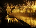 Empty night restaurant, lot of tables and chairs with noone, magic fairy lights on trees like christmas celebration Royalty Free Stock Photo