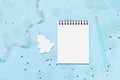 Empty note pad on blue frozen festive background with confetti and sparkles.