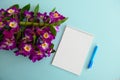 Empty Notebook, Blue Pen and Pink Orchid Flower Bloom  on a Light Blue Background Royalty Free Stock Photo