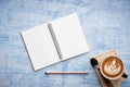 Empty Notebook with cup of coffee latte on blue abstract background Royalty Free Stock Photo