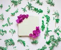 Empty notebook decorated purple flowers on a white background, top view. Notepad decorated with green leaves and violet. Flat lay.