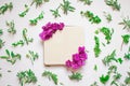 Empty notebook decorated purple flowers on a white background, top view. Notepad decorated with green leaves and violet. Flat lay.