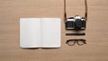 Notebook, retro camera, glasses and pen on wooden table.