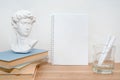 Empty notebook on wooden table with books and small David bust sculpture. Minimal work space, copy space. Education and art Royalty Free Stock Photo
