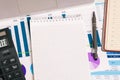 Empty Notepad with a calculator on the background of statistical graphs. Office Desk with Notepad, pen and laptop. Business Royalty Free Stock Photo