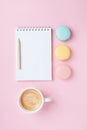 Empty notepad, coffee and colorful macaron on pink pastel desk top view. Cozy morning breakfast. Fashion flat lay.