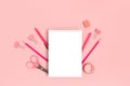 Empty notepad template with office supplies on a pink pastel background.