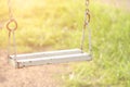 Empty old rusted metal swing in playground at the morning with yellow sunlight.