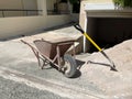 An empty old rusty hand wheelbarrow and shovel next to the pile of sand. Royalty Free Stock Photo