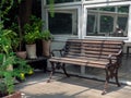 Empty old wooden bench on terrace in front of the old white glass house near the green houseplant and garden Royalty Free Stock Photo
