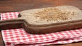 Empty old wooden cutting board and folded red and white cotton kitchen napkin on a wooden brown background, top view, copy space Royalty Free Stock Photo