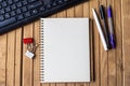 Empty Open Clipped Journal Beside Keyboard Pens On Top Of The Wooden Desk. Royalty Free Stock Photo
