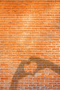 Empty orange brick wall background texture with hands making love heart shadow.