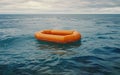 An empty orange inflatable life raft adrift on the ocean waves, symbolizing isolation and danger. Royalty Free Stock Photo