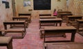 Empty ordinary classroom in African school poor conditions wooden table chairs Royalty Free Stock Photo