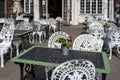 Empty outdoor cozy cafe with beautiful white chairs and wooden tables decorated with red flowers geranium. Restaurant on the Royalty Free Stock Photo