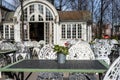 Empty outdoor cozy cafe with beautiful white chairs and wooden tables decorated with red flowers geranium. Restaurant on the Royalty Free Stock Photo