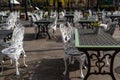 Empty outdoor cozy cafe with beautiful white chairs and wooden tables decorated with red flowers geranium. Restaurant on the Royalty Free Stock Photo