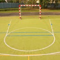 Empty outdoor handball playground, plastic light green surface on ground. Empty gate. Royalty Free Stock Photo