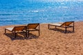 empty outdoor lounge chairs on sandy beach near blue water. Royalty Free Stock Photo