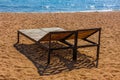 empty outdoor lounge chairs on sandy beach near blue water. Royalty Free Stock Photo