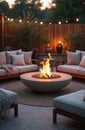 Empty outdoor lounge seating area with fire pit and string lights. Cozy sofas arranged around concrete fire bowl. Evening scene Royalty Free Stock Photo