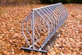 Empty outdoor metal bicycle rack on background of fallen oak leaves in the Fall,
