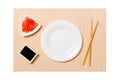 Empty oval white plate with chopsticks for sushi, ginger and soy sauce on brown sushi mat background. Top view with copy space for Royalty Free Stock Photo
