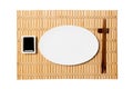 Empty oval white plate with chopsticks for sushi and soy sauce on yellow bamboo mat background. Top view with copy space for you Royalty Free Stock Photo