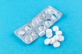 Empty pack with white pills packed in blister with copy space on blue background. Focus on foreground, soft bokeh Royalty Free Stock Photo