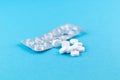 Empty pack with white pills packed in blister with copy space on blue background. Focus on foreground, soft bokeh Royalty Free Stock Photo