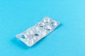 Empty pack of white pills packed in blister with copy space on blue background. Focus on foreground, soft bokeh Royalty Free Stock Photo