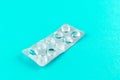 Empty pack of white pills packed in blister with copy space on turquoise background. Focus on foreground, soft bokeh. Pharmacy dru Royalty Free Stock Photo