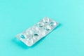 Empty pack of white pills packed in blister with copy space on turquoise background. Focus on foreground, soft bokeh. Pharmacy dru Royalty Free Stock Photo