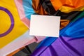 Empty paper blank on Rainbow LGBTQIA flag made from silk material. Mock up template copy space for your text. Symbol of
