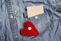 Empty paper card in pocket of denim shirt and red heart. Copy sp