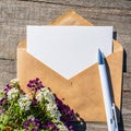An empty paper postcard, an envelope and alissum flowers on a wooden background Royalty Free Stock Photo