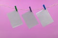 Empty paper sheets for notes, clothespins pink colored background Royalty Free Stock Photo