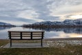 An empty park bench on a cold December day at Osoyoos Lake in BC, Canada Royalty Free Stock Photo
