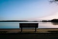 An empty park bench by a lake Royalty Free Stock Photo